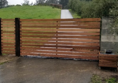Flat Top Driveway Gate w/ Horizontal Wood Slats. Gate Operator Hidden Behind Coordinating Panel
