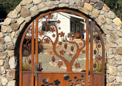 Arch Top Pedestrian Gate - Natural Patina Bare Metal w/ Open Grape Vine Design Top & Reverse Cut Out Bottom. Companion Driveway Gate DGB-170